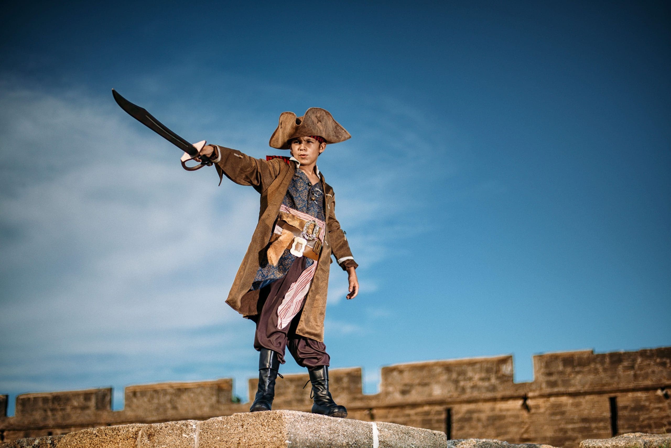 Photograph of a boy dressed as a pirate and holding in his hand a pirate sword.