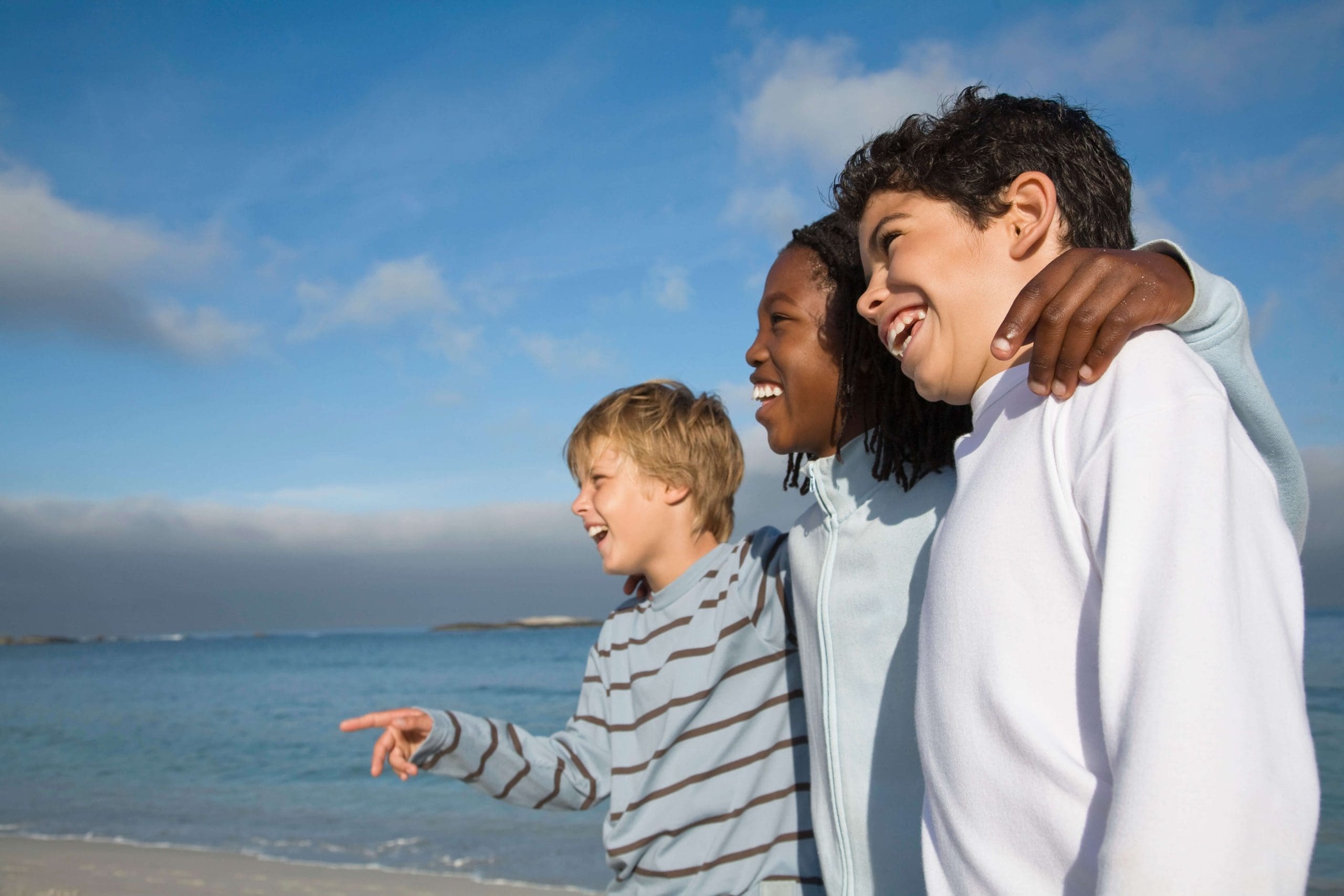 The power of laughter: Photograph of a three boys laughing on beach. 